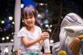 Happy Asian girl riding on a horse merry go round.