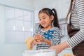 Happy girl is smiling while making flour bread with her mother in home kitchen, for child activity concept Royalty Free Stock Photo