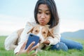 Happy Asian girl Take a photo a dog and playing with smartphone On the green lawn together close-up at morning Royalty Free Stock Photo