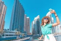 Asian girl taking selfie photo on a smartphone while walking on a promenade in Dubai Marina district. Travel and lifestyle Royalty Free Stock Photo