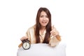 Happy Asian girl thumbs up with pillow and alarm clock Royalty Free Stock Photo