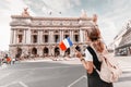 Asian girl traveler with french flag near the main Facade of the Opera Garnier in the historic building of the Academy of Royalty Free Stock Photo