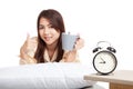 Happy Asian girl wake up , thumbs up with alarm clock and coff Royalty Free Stock Photo