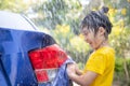 Happy Asian girl washing car on water splashing and sunlight at home Royalty Free Stock Photo