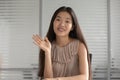 Happy Asian girl waving to camera talking on video call