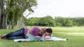 Happy Asian grandfather and granddaughter in the park spending free time together reading outdoors