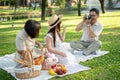 A happy Asian grandfather is taking a picture of his wife and granddaughter while enjoying a picnic Royalty Free Stock Photo