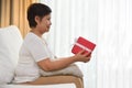 Happy Asian Grandmother holding a red gift box.