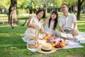 Happy Asian grandparents and granddaughter are picnicking and having fun in the park together Royalty Free Stock Photo