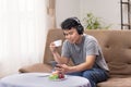 Happy asian guy sitting relax on sofa , listen and pose share good news at social media via cellphone Royalty Free Stock Photo