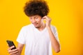 Happy asian handsome man with curly hair he smiling enjoying listening to music on earphones using a mobile smartphone Royalty Free Stock Photo