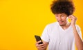 Happy asian handsome man with curly hair he smiling enjoying listening to music on earphones using a mobile smartphone Royalty Free Stock Photo