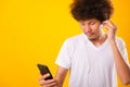 Happy asian handsome man with curly hair he smiling enjoying listening to music on earphones using a mobile smartphone Royalty Free Stock Photo