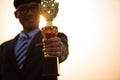 A happy asian handsome young businessman in a business suit showing golden award winning trophy during sunset sunrise mountain in Royalty Free Stock Photo