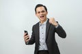 happy asian indonesian business man in suit holding smart phone on isolated background Royalty Free Stock Photo