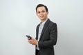 happy asian indonesian business man in suit holding smart phone on isolated background Royalty Free Stock Photo