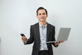 happy asian indonesian business man in suit holding smart phone and laptop computer on isolated background Royalty Free Stock Photo