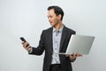 happy asian indonesian business man in suit holding smart phone and laptop computer on isolated background Royalty Free Stock Photo