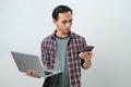 Happy asian indonesian man holding smartphone and laptop computer on isolated background Royalty Free Stock Photo