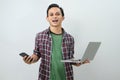 Happy asian indonesian man holding smartphone and laptop computer on isolated background Royalty Free Stock Photo