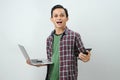 Happy asian indonesian man holding smartphone and laptop computer on isolated background Royalty Free Stock Photo