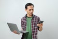 Happy asian indonesian man holding smartphone and laptop computer on isolated background Royalty Free Stock Photo