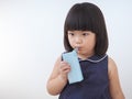 Happy asian kid girl drinking milk from carton box with straw, Blank juice package in hand of healthy child