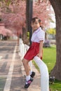 Happy Asian kindergarten little girl in garden under the blossom sakura tree