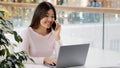 Happy Asian Korean woman freelancer student businesswoman holding mobile phone call working with laptop multitasking Royalty Free Stock Photo