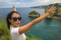 Happy Asian Korean woman in sunglasses enjoying amazing coast scene from view point at tropical paradise beach with diamond rock Royalty Free Stock Photo