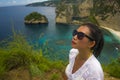 Happy Asian Korean woman in sunglasses enjoying amazing coast scene from view point at tropical paradise beach with diamond rock Royalty Free Stock Photo