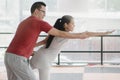 Happy asian lady exercising yoga with personal home trainer. Man helping student posing in yoga position and balance body.