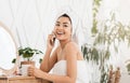 Happy asian lady talking on phone, sitting next to mirror Royalty Free Stock Photo