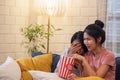 Happy asian lesbain couple watching scary movie on television together and eating popcorn at sofa in night time at home with chill Royalty Free Stock Photo