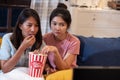 Happy asian lesbain couple watching scary movie on television together and eating popcorn at sofa in night time at home with chill Royalty Free Stock Photo