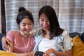 Happy asian lesbain couple watching video on mobile phone together on sofa in night time at home with chill out emotion.woman Royalty Free Stock Photo