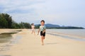 Happy Asian little boy child and girl kid having fun running on tropical sand beach at sunrise. Happy family sister and brother Royalty Free Stock Photo