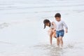Happy asian little boy and girl playing and running while holding hand on sandy beach with happy smiling face on sunny day Royalty Free Stock Photo