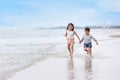 Happy asian little boy and girl playing and running while holding hand on sandy beach with happy smiling face on sunny day Royalty Free Stock Photo