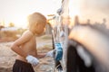 Happy asian little boy playing white soap and using blue sponge to washing the car at outdoor in sunset time Royalty Free Stock Photo