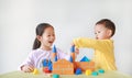 Happy asian little child girl and baby boy playing a colorful wood block toy on table over white background. Sister and her Royalty Free Stock Photo