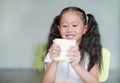 Happy Asian little child girl eating bread with deliciousness at home