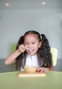 Happy Asian little child girl eating healthy food with deliciousness at home