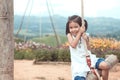 Happy asian little child girl having fun to play on wooden swings