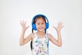 Happy asian little child girl listening music by blue headphones and looking at camera on white background Royalty Free Stock Photo