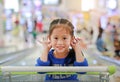 Happy Asian little child girl sitting in the trolley during family shopping in the market Royalty Free Stock Photo