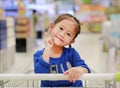 Happy Asian little child girl sitting in the trolley during family shopping in the market Royalty Free Stock Photo