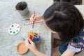 Asian girl studying and learning the art,the kid using paintbrush to painting water color on the potted plant made of pottery,