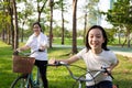 Happy asian little girl child with bicycle in outdoor park,smiling daughter with mother on a bike ride together,family activities Royalty Free Stock Photo