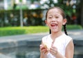 Happy Asian little girl eating bread with Stuffed Strawberry-filled dessert and Stained around her mouth in garden outdoor Royalty Free Stock Photo